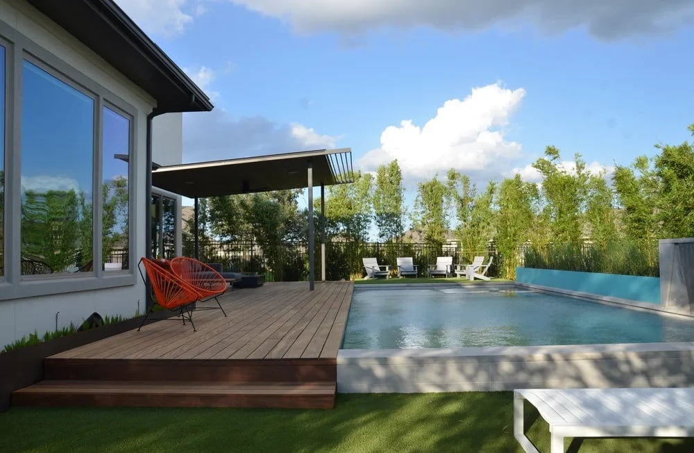 Geometric pool with a turquoise tile wall and ipe deck beside a covered patio and bamboo screen