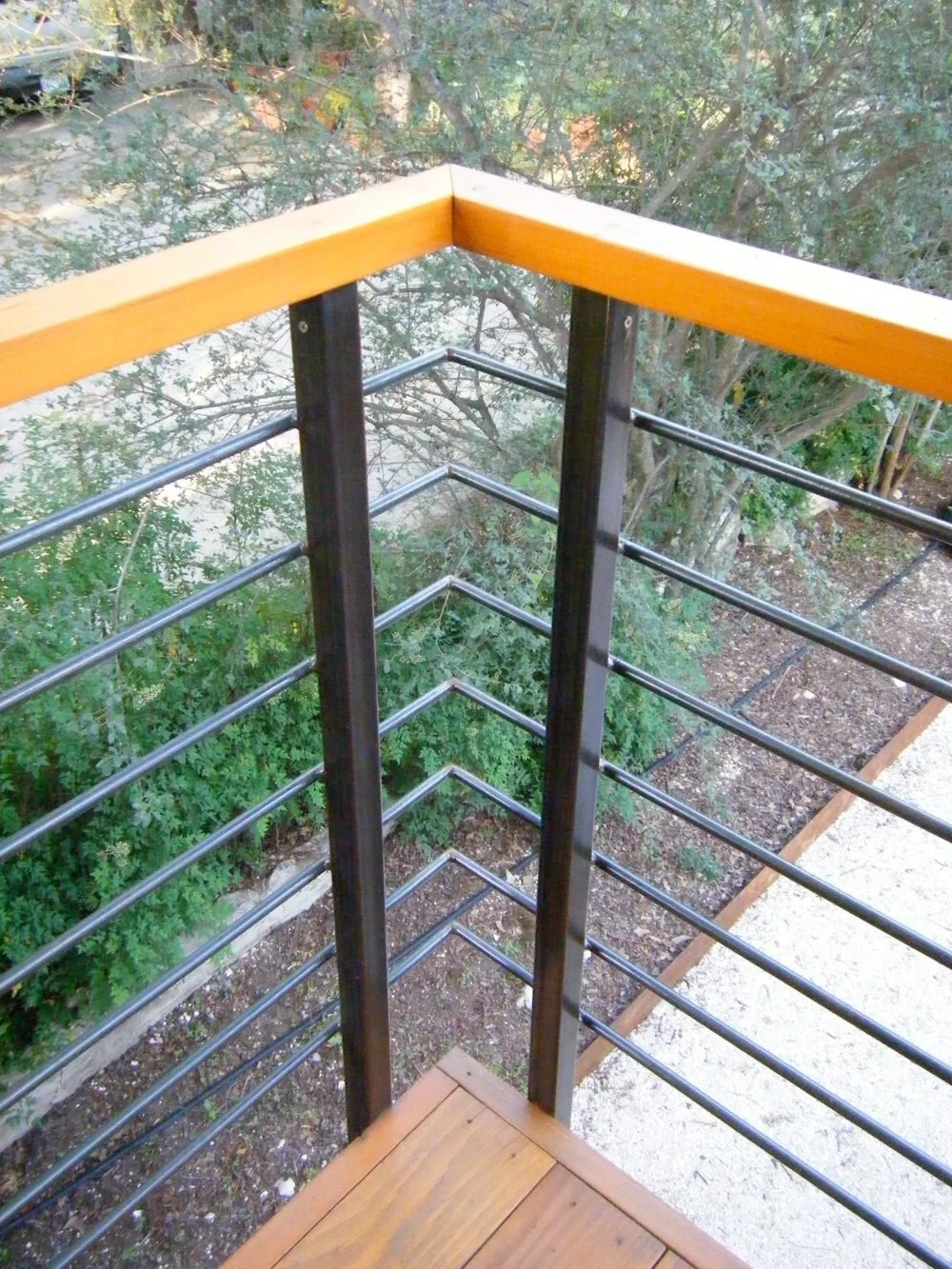 Cable railing with a wood top rail on an elevated deck overlooking a wooded slope