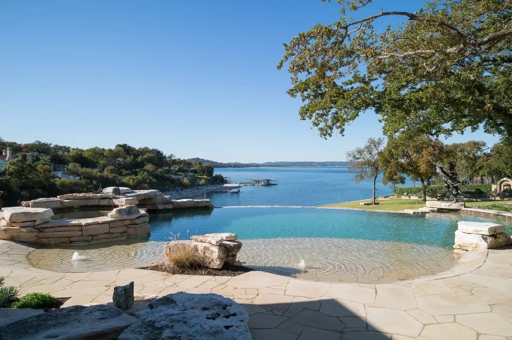 Freeform infinity pool overlooking Lake Travis, with a stone spa and natural flagstone deck