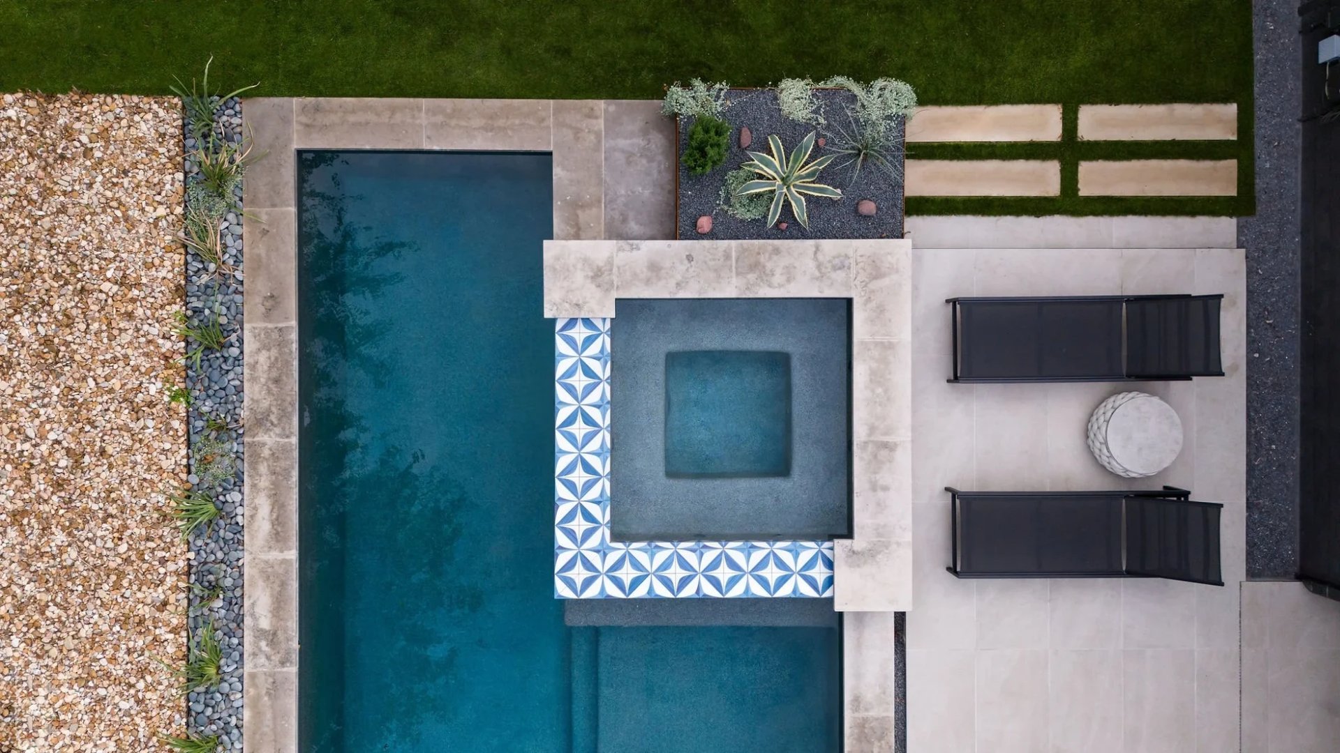 Overhead view of a geometric pool with a tiled spa, loungers, and planters by a modern home