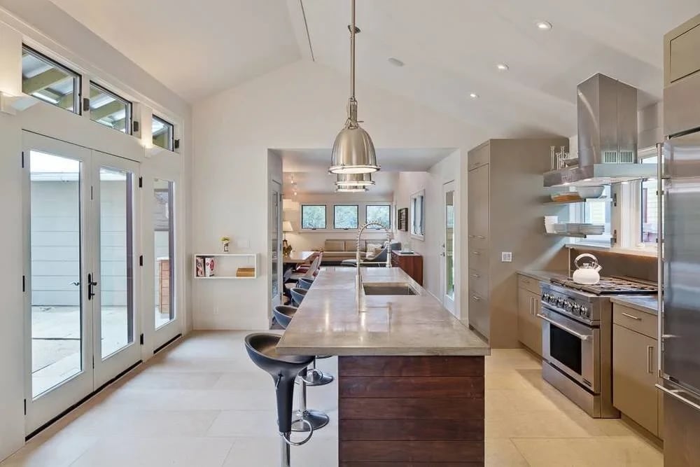 Modern kitchen with a concrete-topped wood island, stainless range and french doors