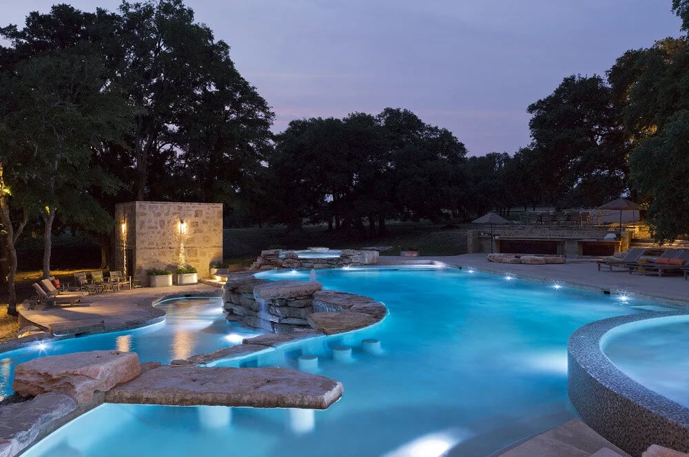 Custom freeform pool with rock features blending into a natural Austin backyard